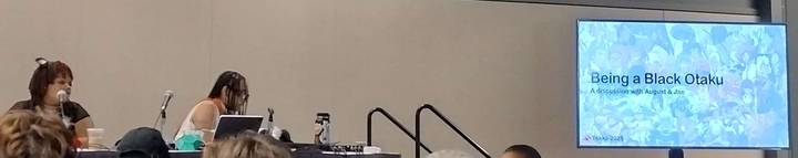 Two Black women getting ready to begin their panel, setting up their table and presentation.