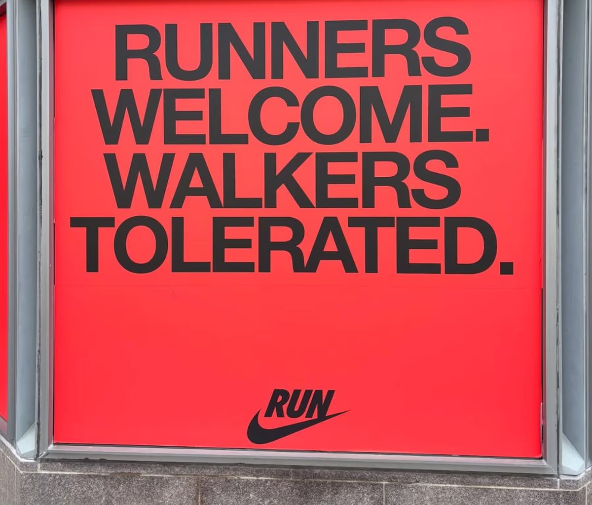 Sign with red background and black text that says "RUNNER WELCOME. WALKERS TOLERATED."