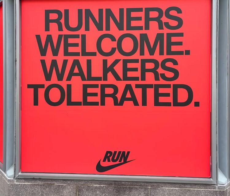 Sign with red background and black text that says "RUNNER WELCOME. WALKERS TOLERATED."