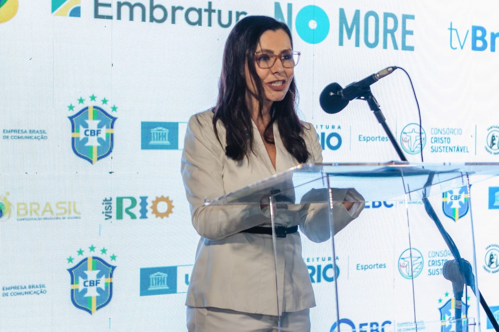 Speaker at the podium at the Brazil Says NO MORE launch, in front of a partner logo wall