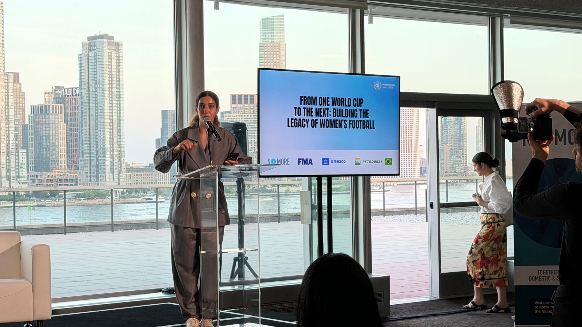 Speaker at the From One World Cup to the Next reception at UN Headquarters, with the East River behind