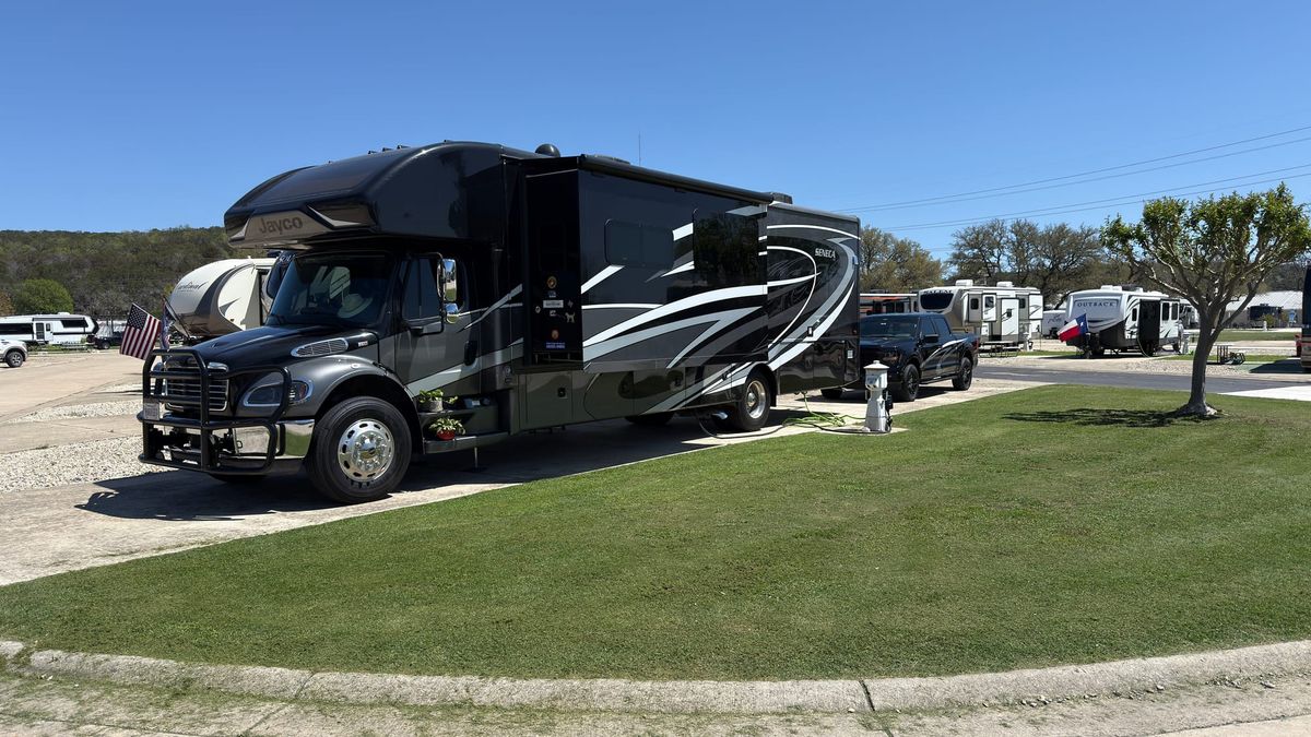 Harriet, a large Jayco Super C motorhome, parked beside Vern on a landscaped RV site with green grass at Buckhorn Lake Resort near Kerrville, Texas.
