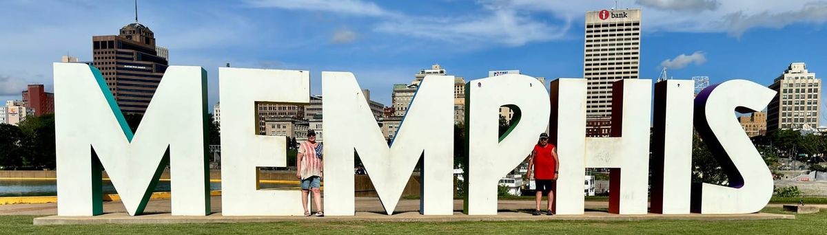 Phil and Lisa standing among the large white MEMPHIS letters on Mud Island with the downtown Memphis skyline behind them.