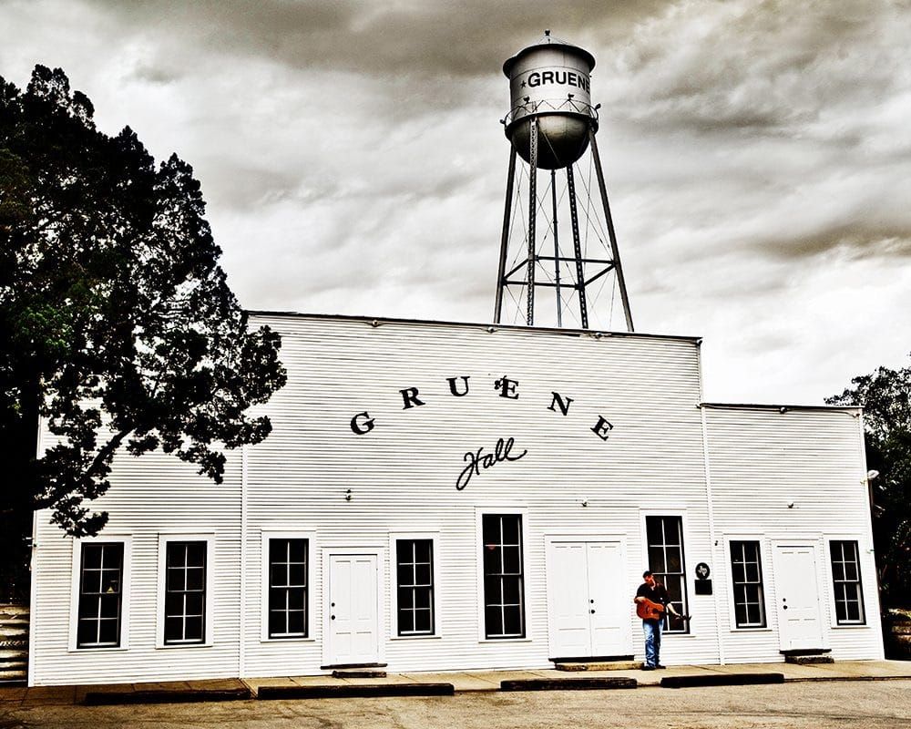 White wooden exterior of Gruene Hall with its water tower rising above the historic dance hall.