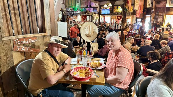 Phil and Lisa seated at a table with food inside a busy rustic restaurant in Tombstone, Arizona.