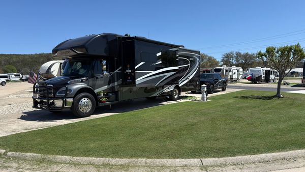 Harriet, a large Jayco Super C motorhome, parked beside Vern on a landscaped RV site with green grass at Buckhorn Lake Resort near Kerrville, Texas.