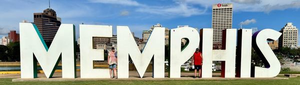 Phil and Lisa standing among the large white MEMPHIS letters on Mud Island with the downtown Memphis skyline behind them.