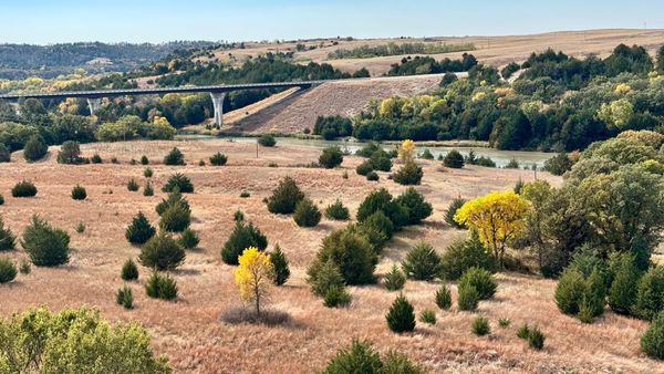 Autumn trees and grassland along the Niobrara River near Valentine, Nebraska, with a bridge crossing the valley.