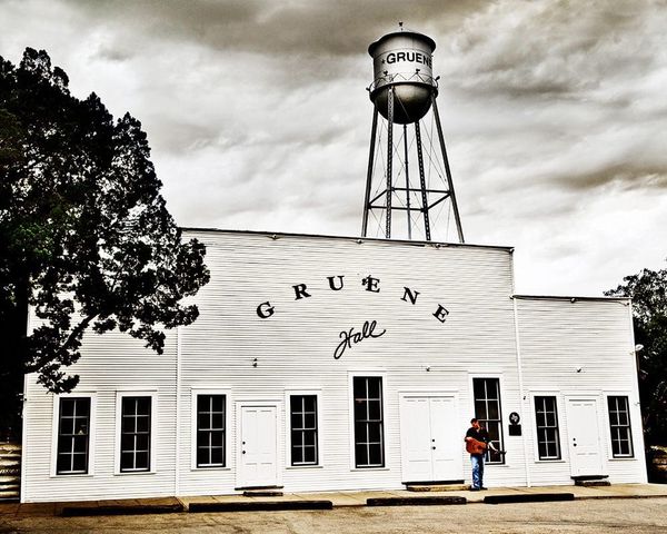 White wooden exterior of Gruene Hall with its water tower rising above the historic dance hall.