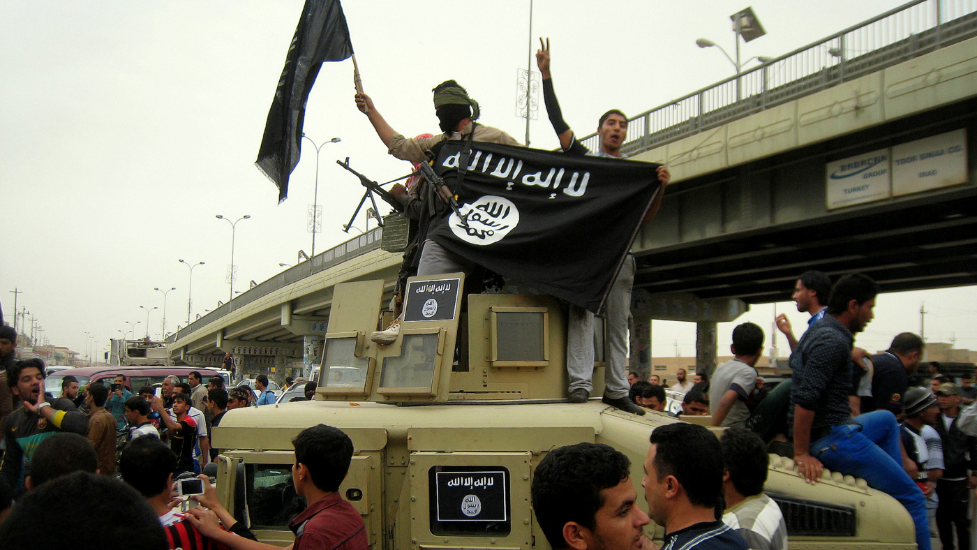 Members of ISIS celebrate on top of a western military vehicle