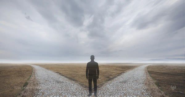 A person standing at a forked path under an open sky, symbolizing conscious choice and inner authority.