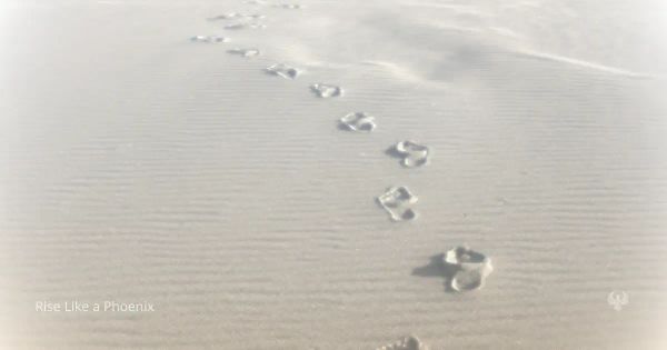 Footprints in sand forming a single path, symbolizing choice, continuity, and the consequences of past actions.