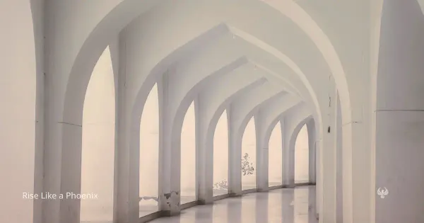 A pale arched corridor with repeating white columns and soft light, symbolizing karmic patterns, repetition, reflection, and the path toward clearer awareness.
