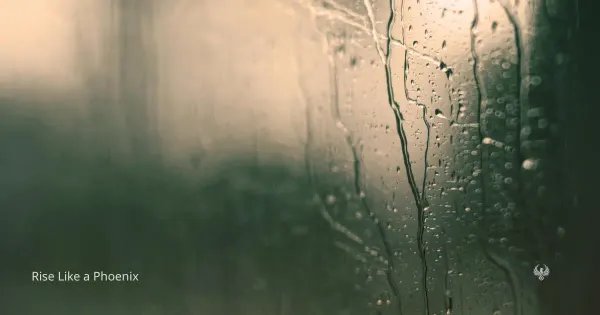A moody, close-up image of rain running down a window, with a soft green and gray blurred background, symbolizing distance, reflection, and emotional separation