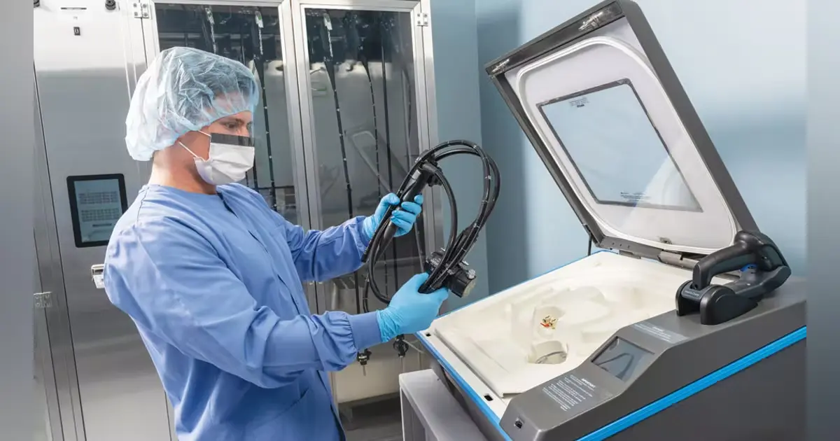Endoscopy technician operating an Endoscope Washer Disinfector (EWD) as part of reprocessing workflow.