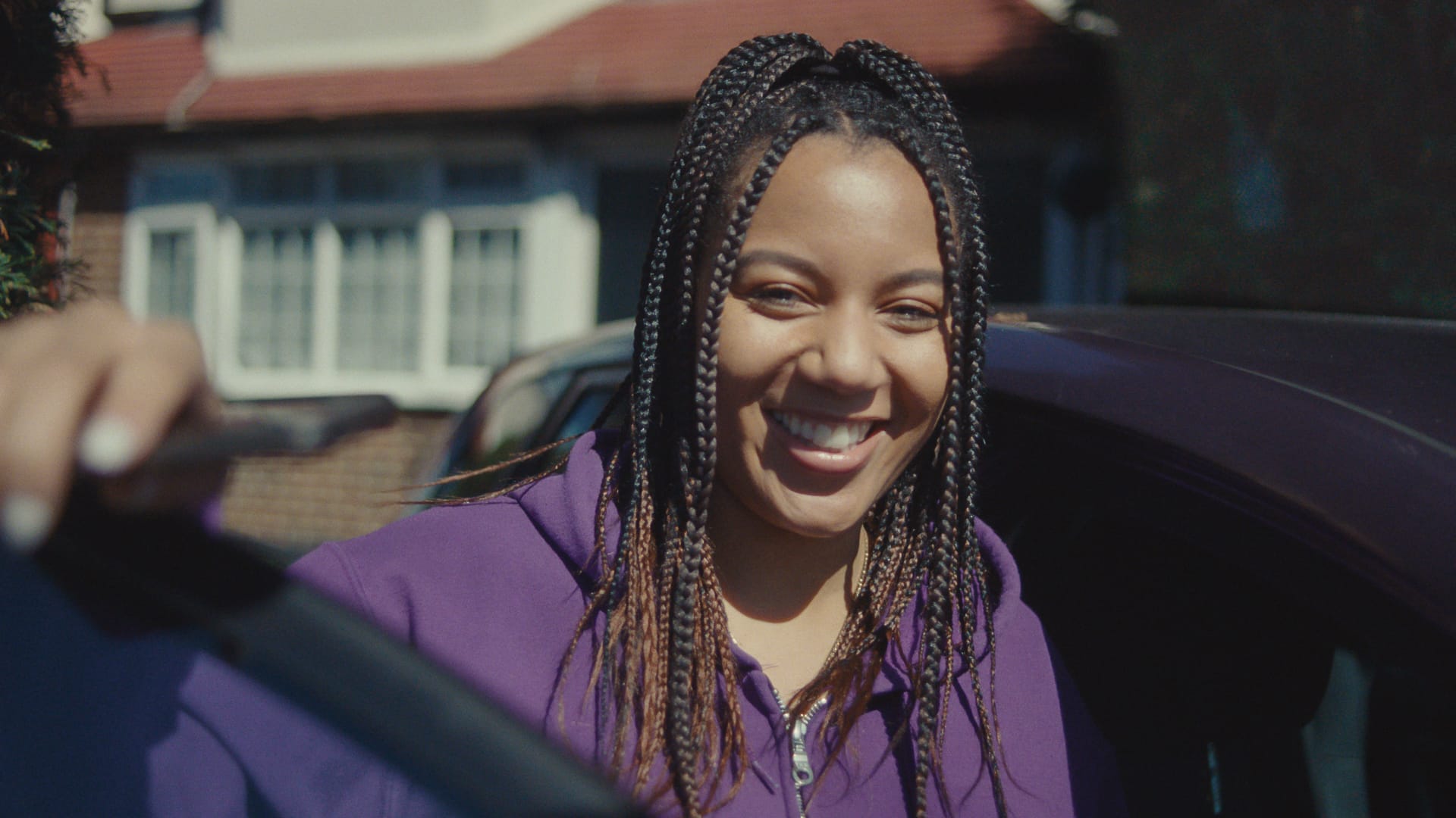 A By Miles member smiling while standing beside their car, representing confidence and ease after successfully connecting their Miles Tracker.