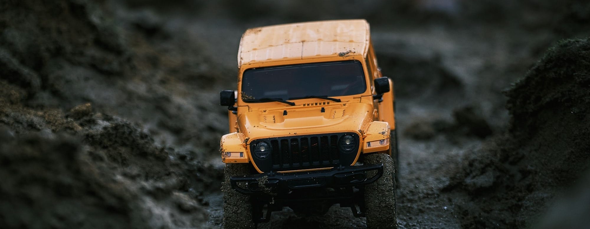 a yellow jeep is parked in the mud