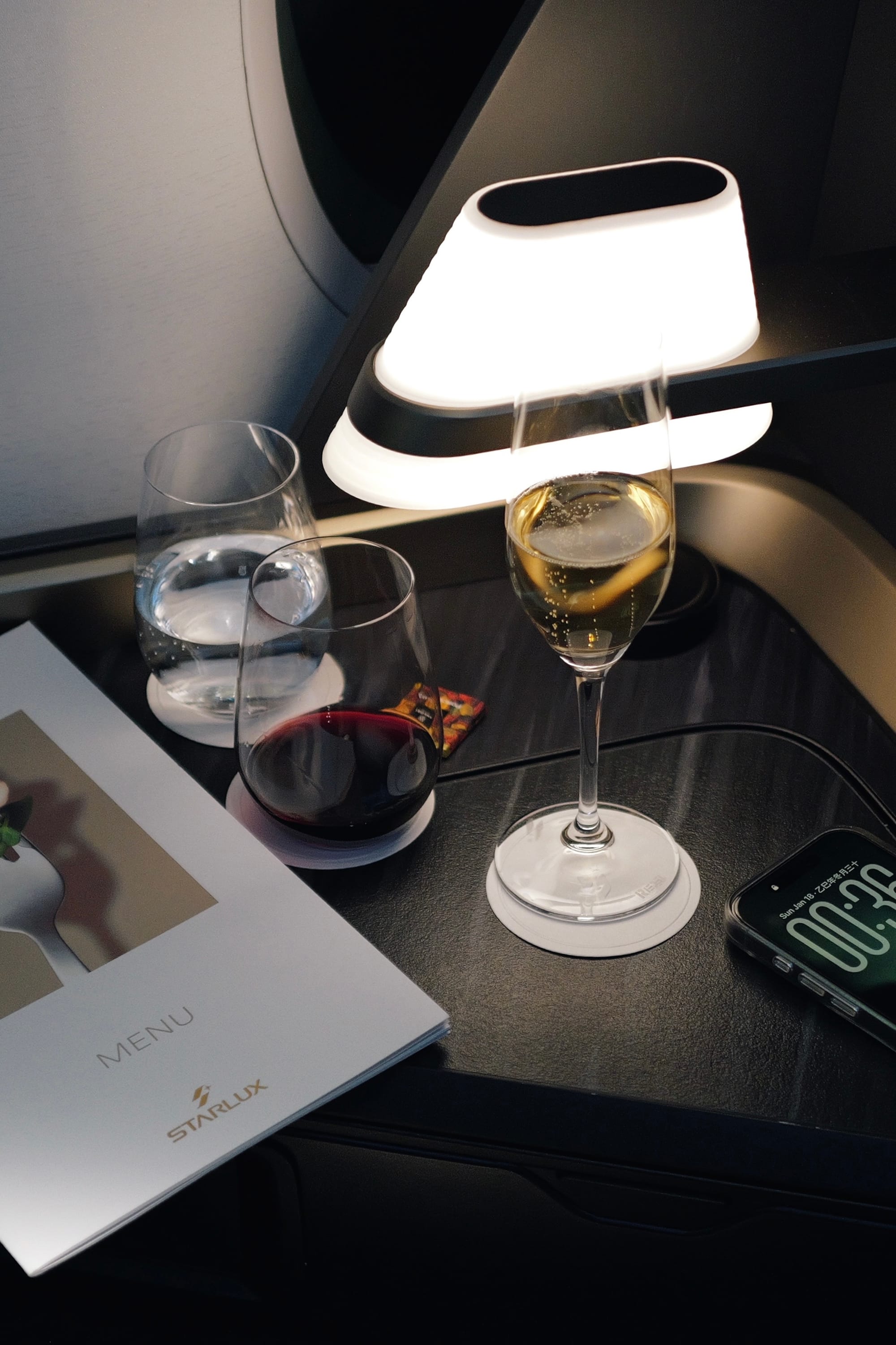 Reading lamp over a glass at the STARLUX business class window seat at night