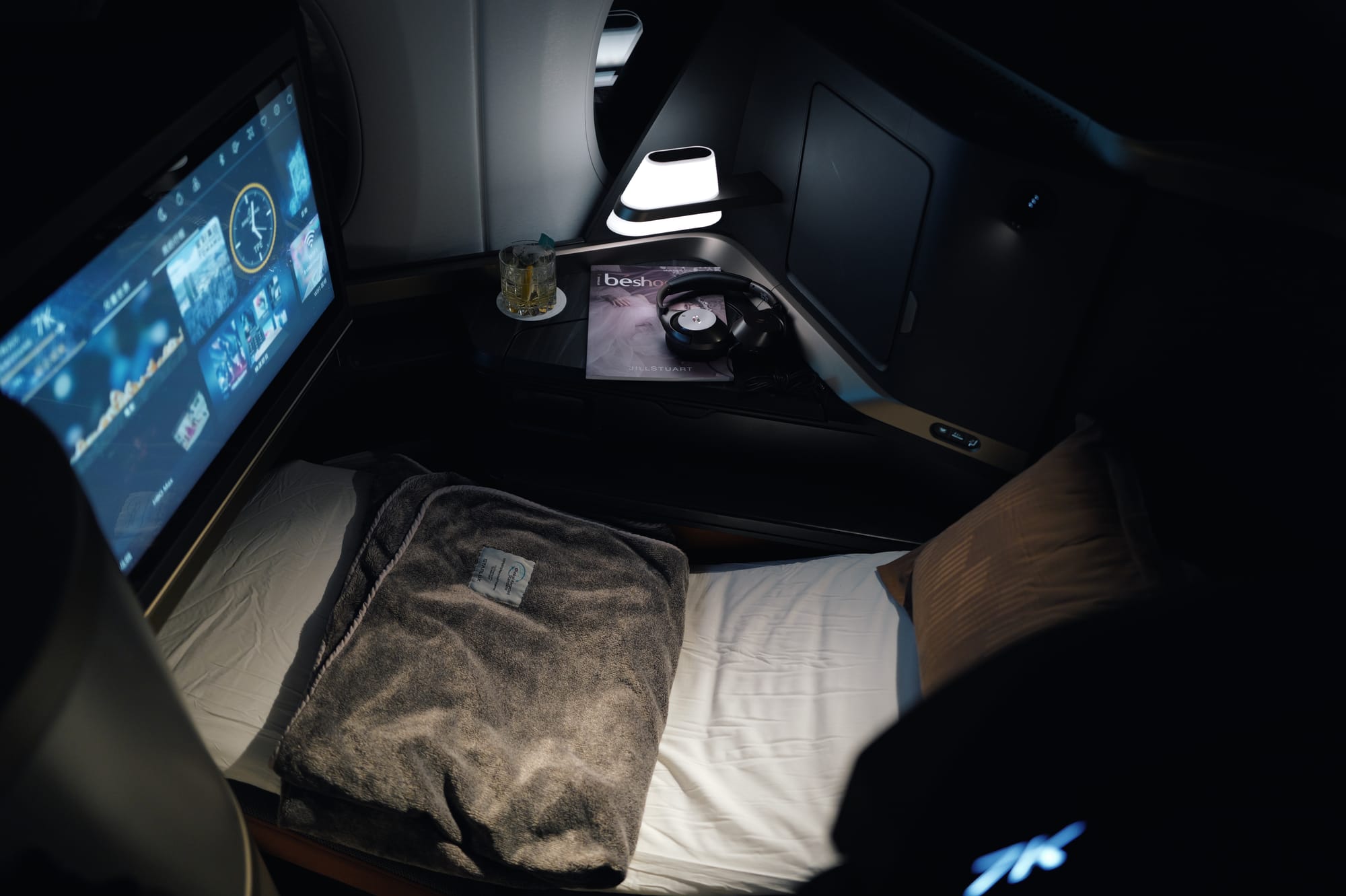 Screen glowing in the darkened STARLUX A350 business class cabin at night