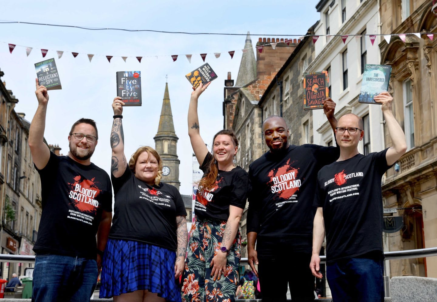 Me on Stirling High Street with the other debut prize shortlisters, holding copies of our books in the air