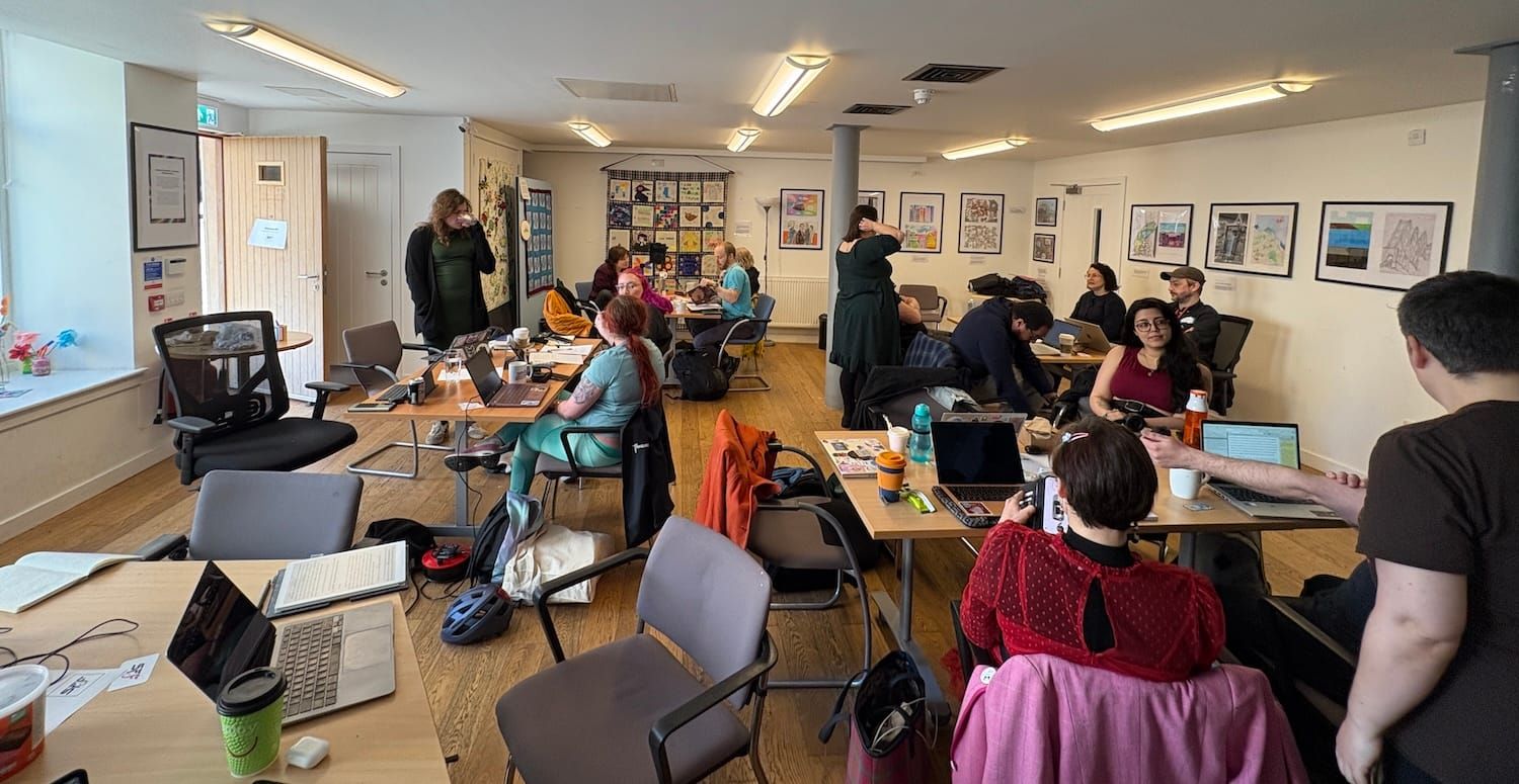 A group of writers around tables and laptops at the Crannie community hub in Edinburgh