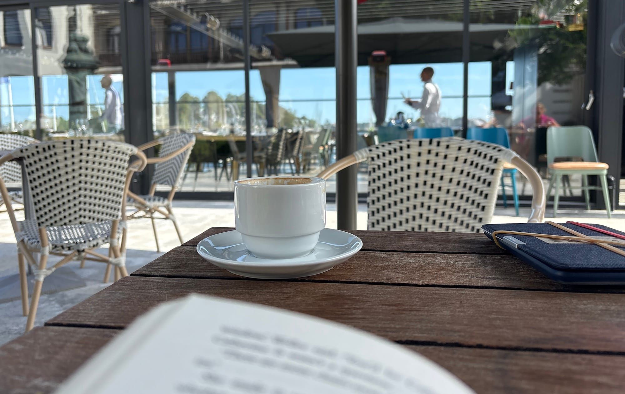 A book, slightly out of focus, with a coffee cup in the background, in focus.