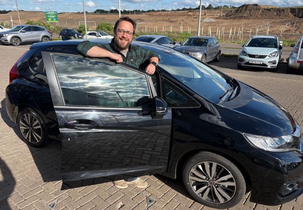 Me, looking very pleased with myself, next to a black Honda Jazz