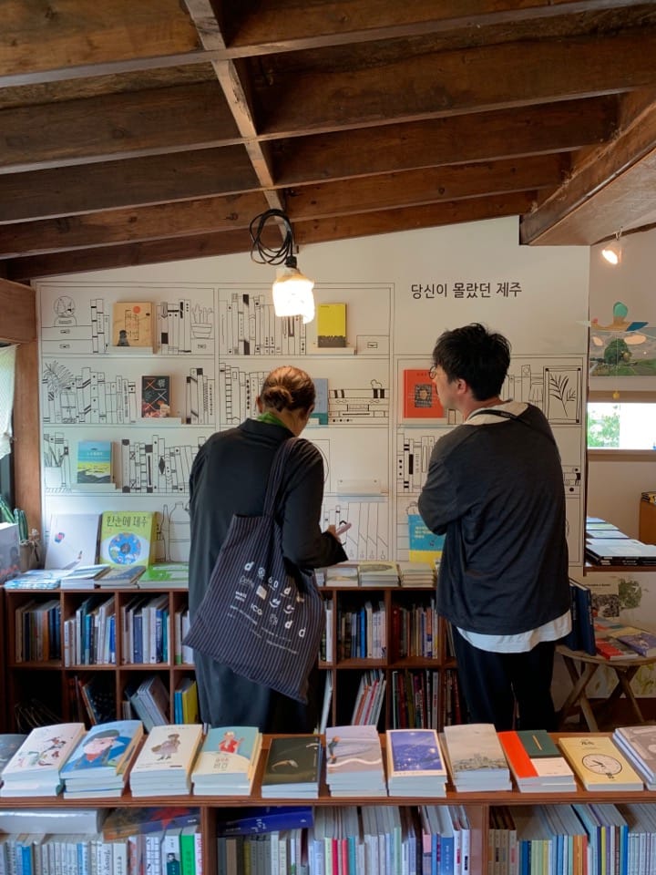 《d design travel 제주》 답사 중 서점에서 책을 살펴보는 두 사람
