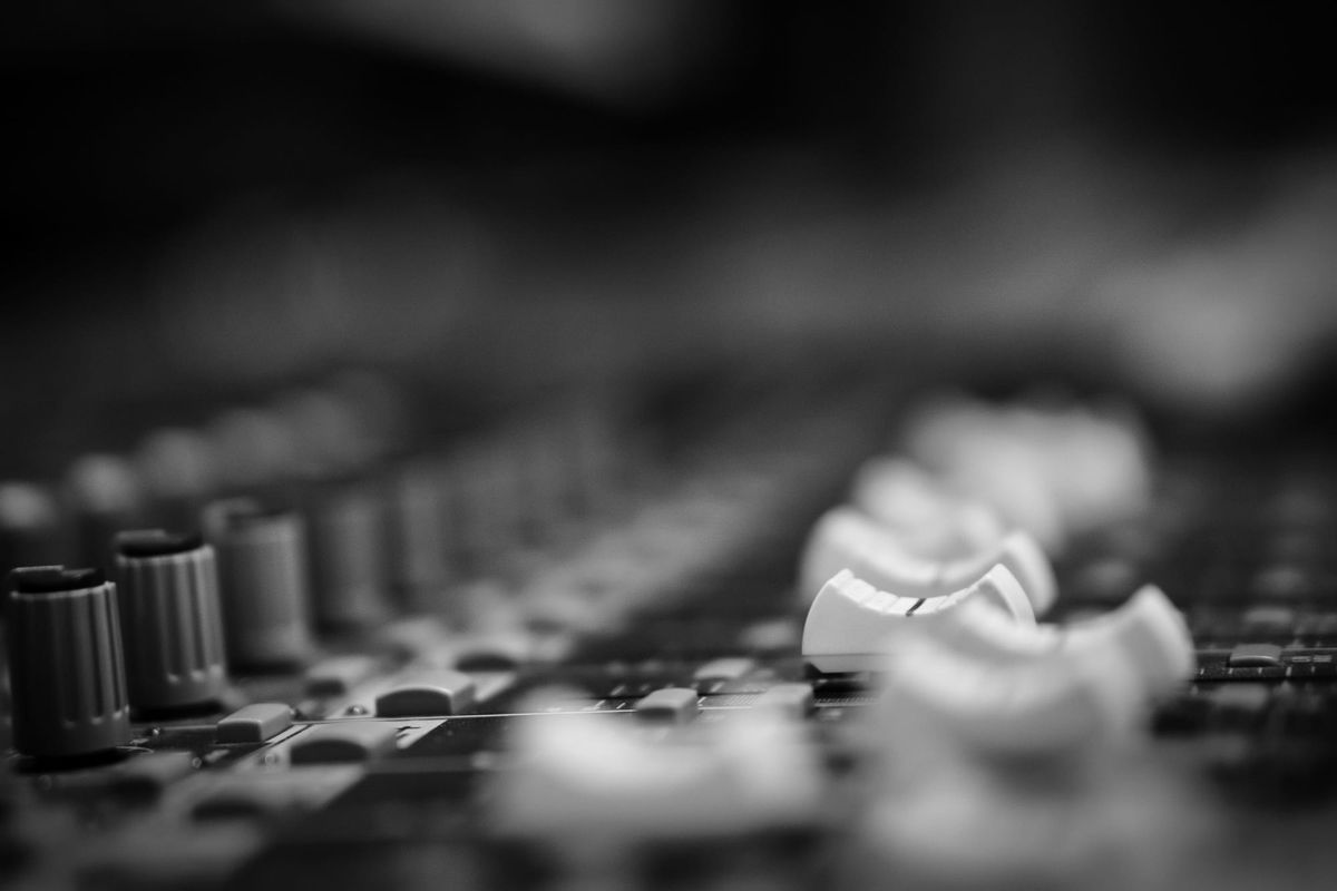 Monochrome close-up of a pale mixer table, with knobs on the left; shallow focus gives the scene a quiet, moody feel.