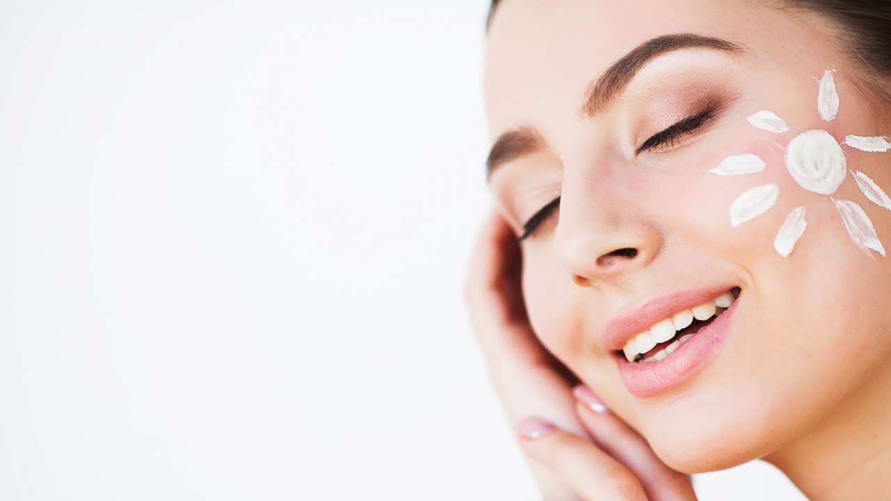 Broad spectrum sunscreen with SPF of 30 or higher used for sun protection, applied to a woman’s cheek to look like the sun.