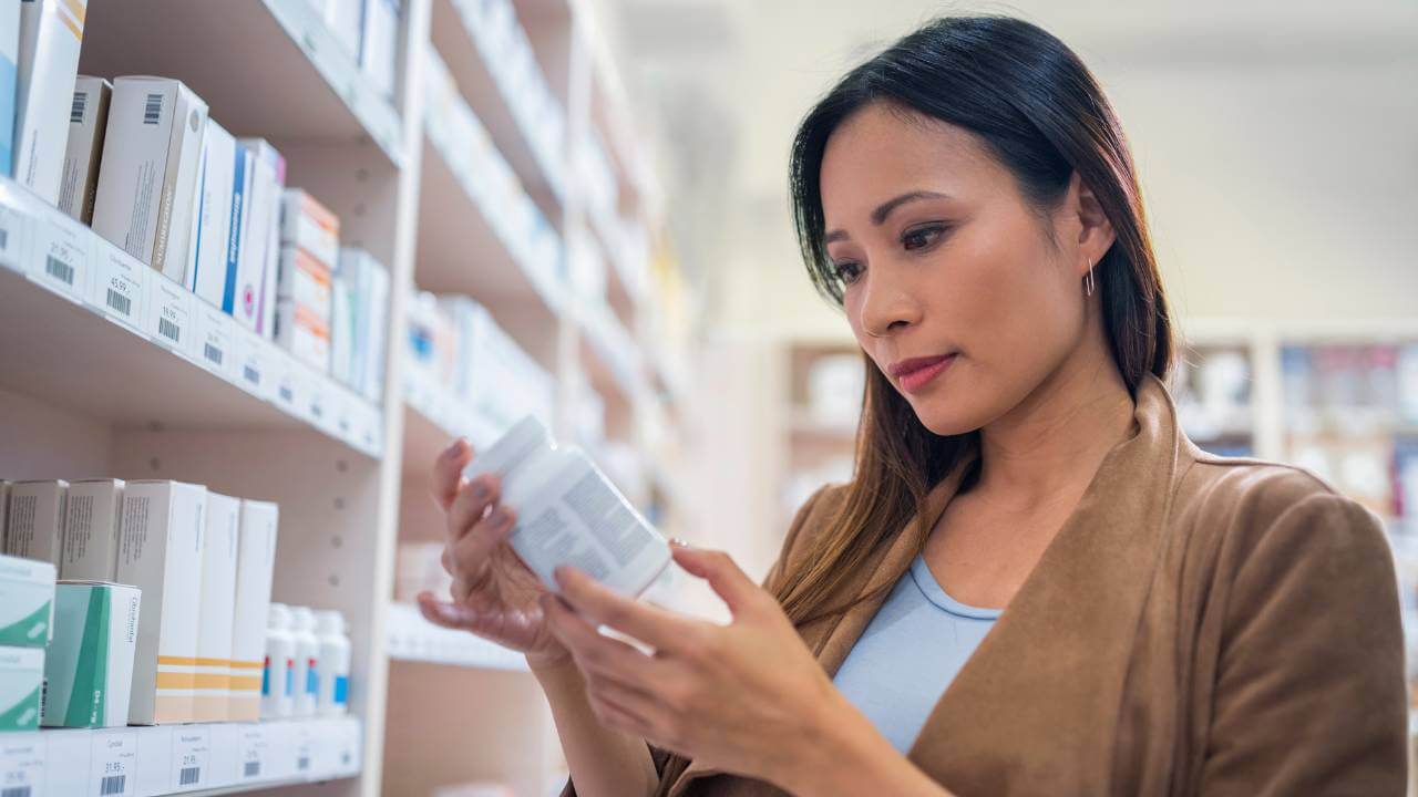 A woman reading a label on a collagen supplement bottle.