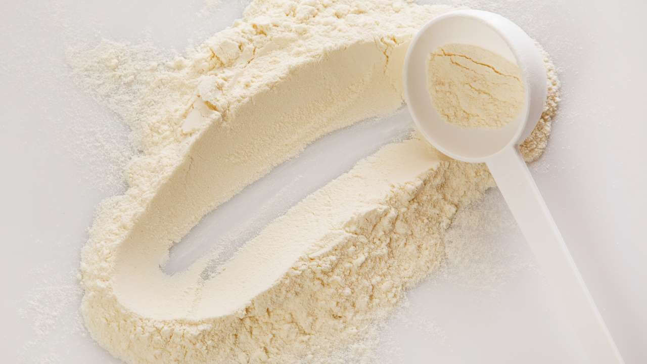 Spoon scooping up a mound of bovine collagen powder on a white background.