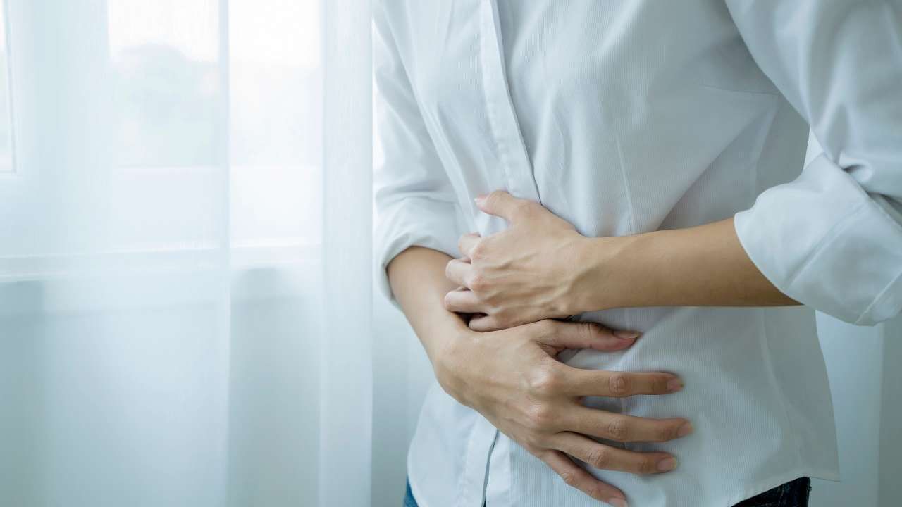 Woman with gastrointestinal issues holding her stomach and in need of a dietary supplement for collagen deficiency. 