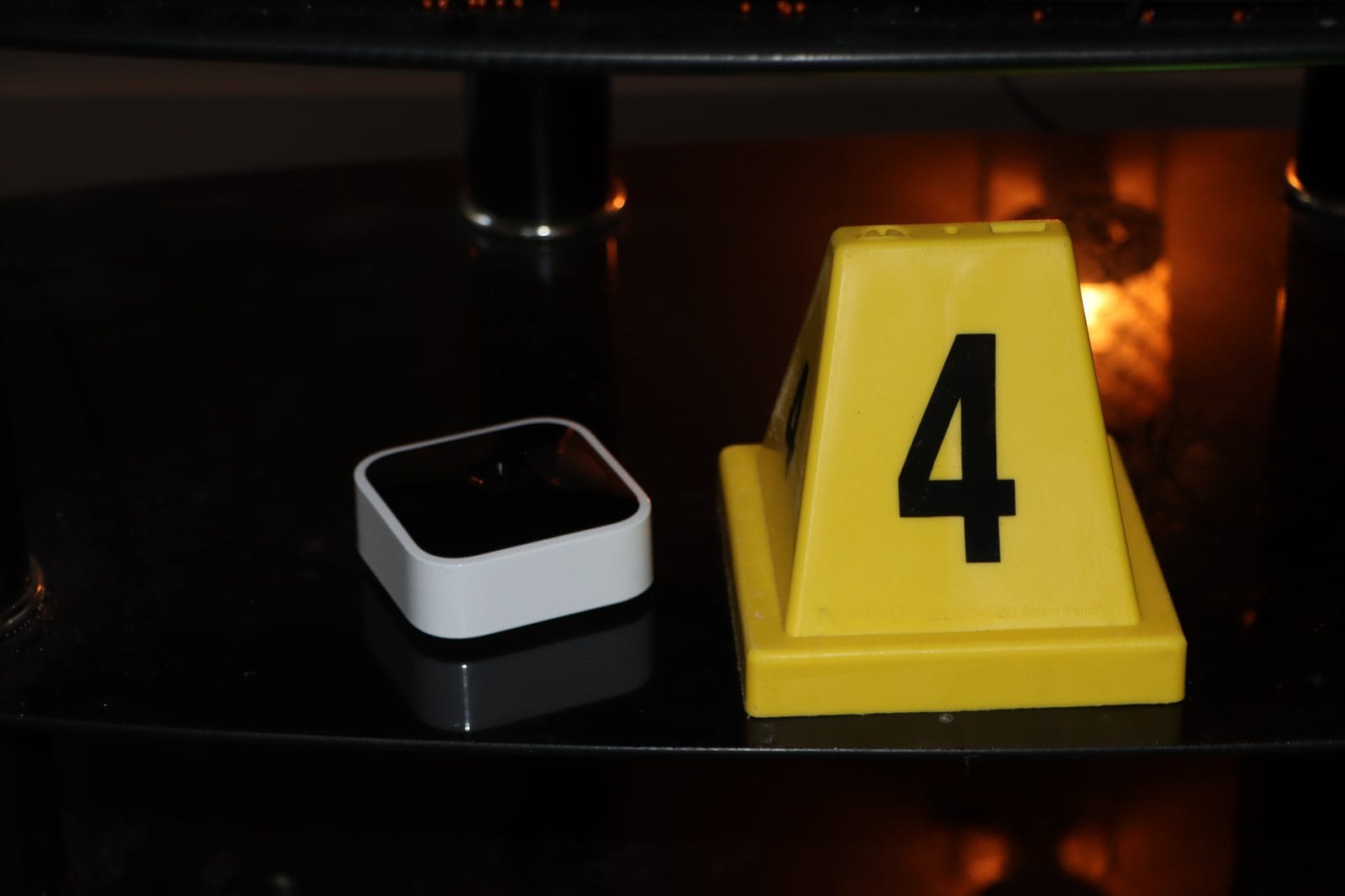 A small white Blink camera on a glass shelf beside a numbered yellow evidence marker.