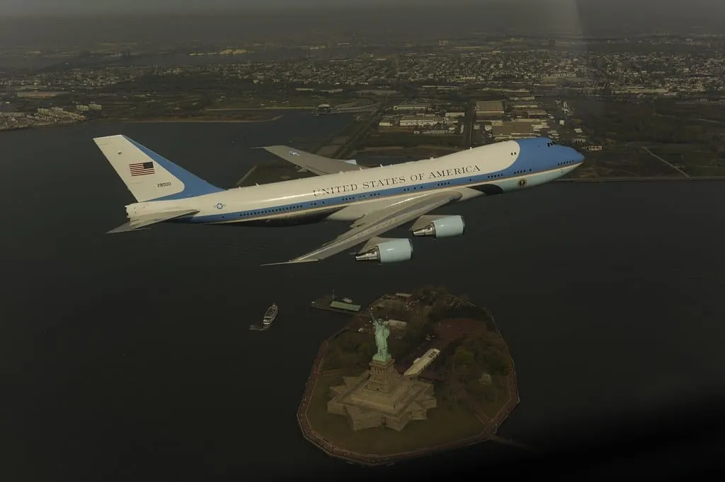 The VC-25 presidential aircraft banking low over the Statue of Liberty with an F-16 escort out of frame.