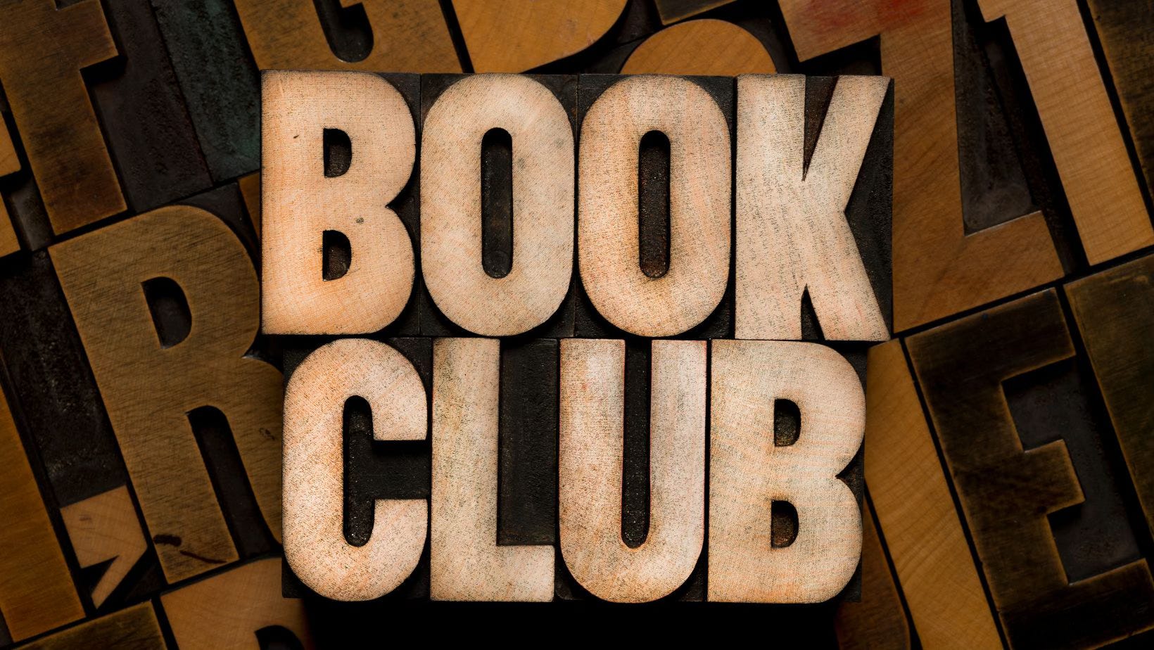Stylized text which reads "BOOK CLUB" in a light wood pattern. The background is various dark colored wood letters in faded relief.