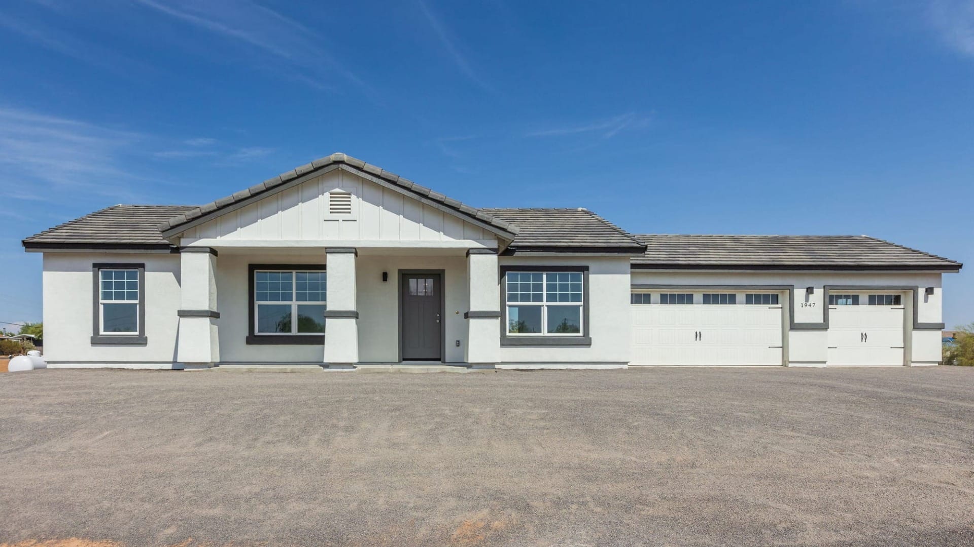A white building in front of a gravel driveway ready to be paved