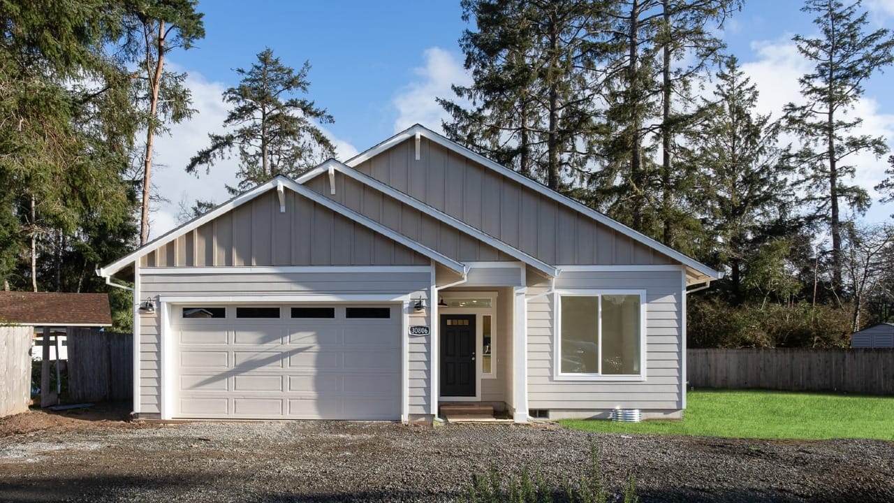 A small tan house with a gravel driveway