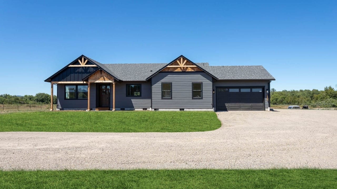 A dark grey house with wood paneling under a blue sky