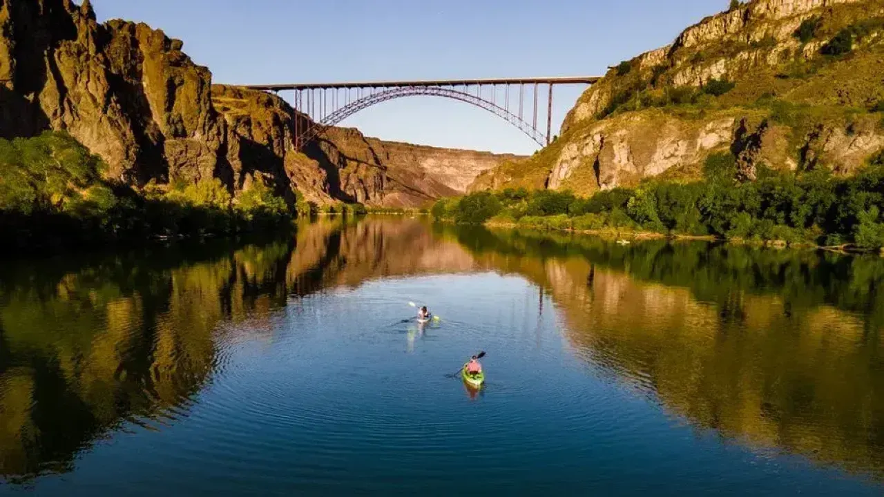 A Lake with people Kayaking with a bridge going over it