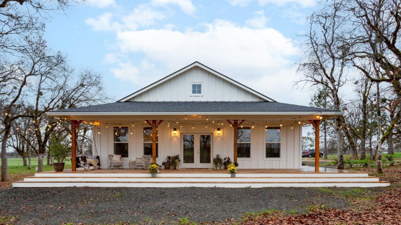 A house with white siding that has lights on the front porch