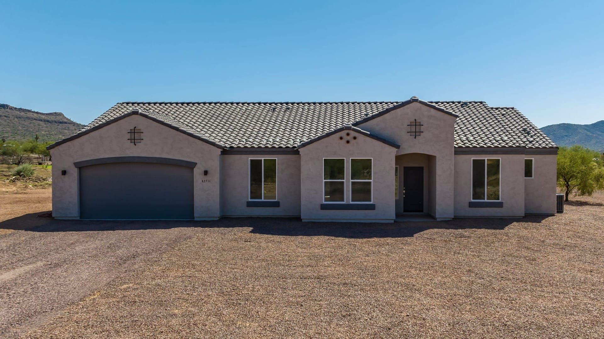 A Stucco house in a gravel lot