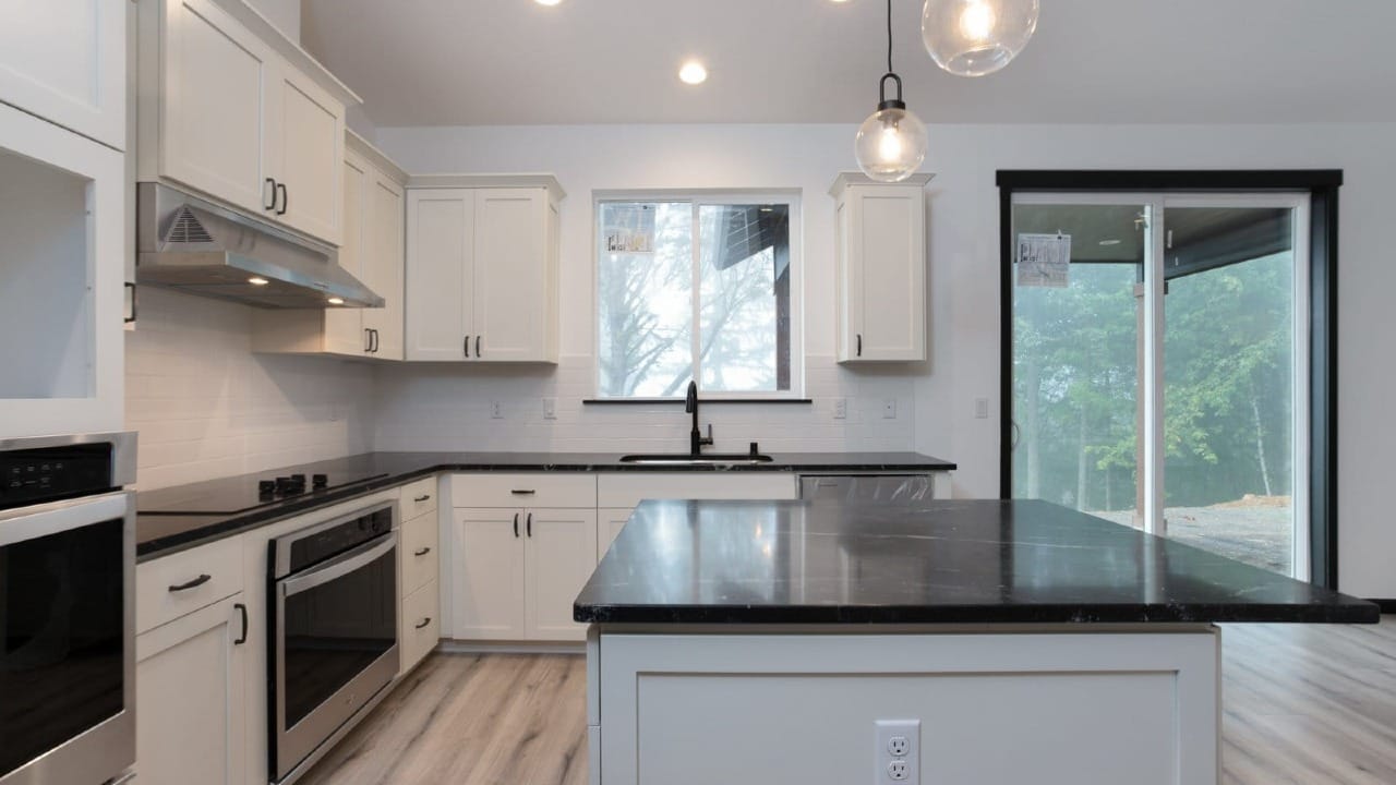 A kitchen with white cabinets and black trim