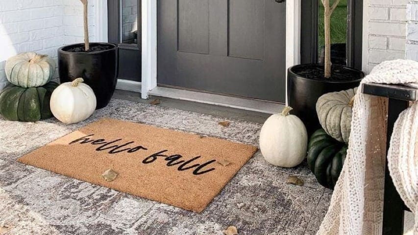 A front porch with a fall throw rug on it