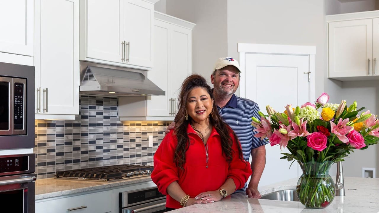 A couple in their new kitchen smiling for the camera