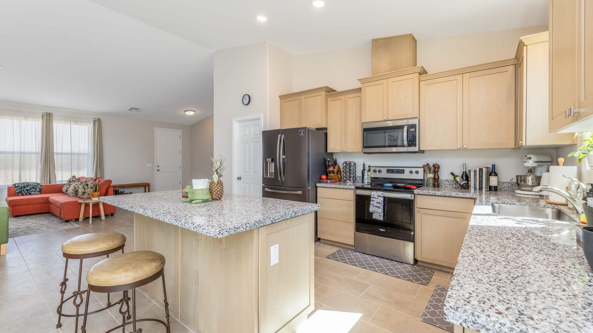 A Kitchen with tan cupboards with the sun shining through a window