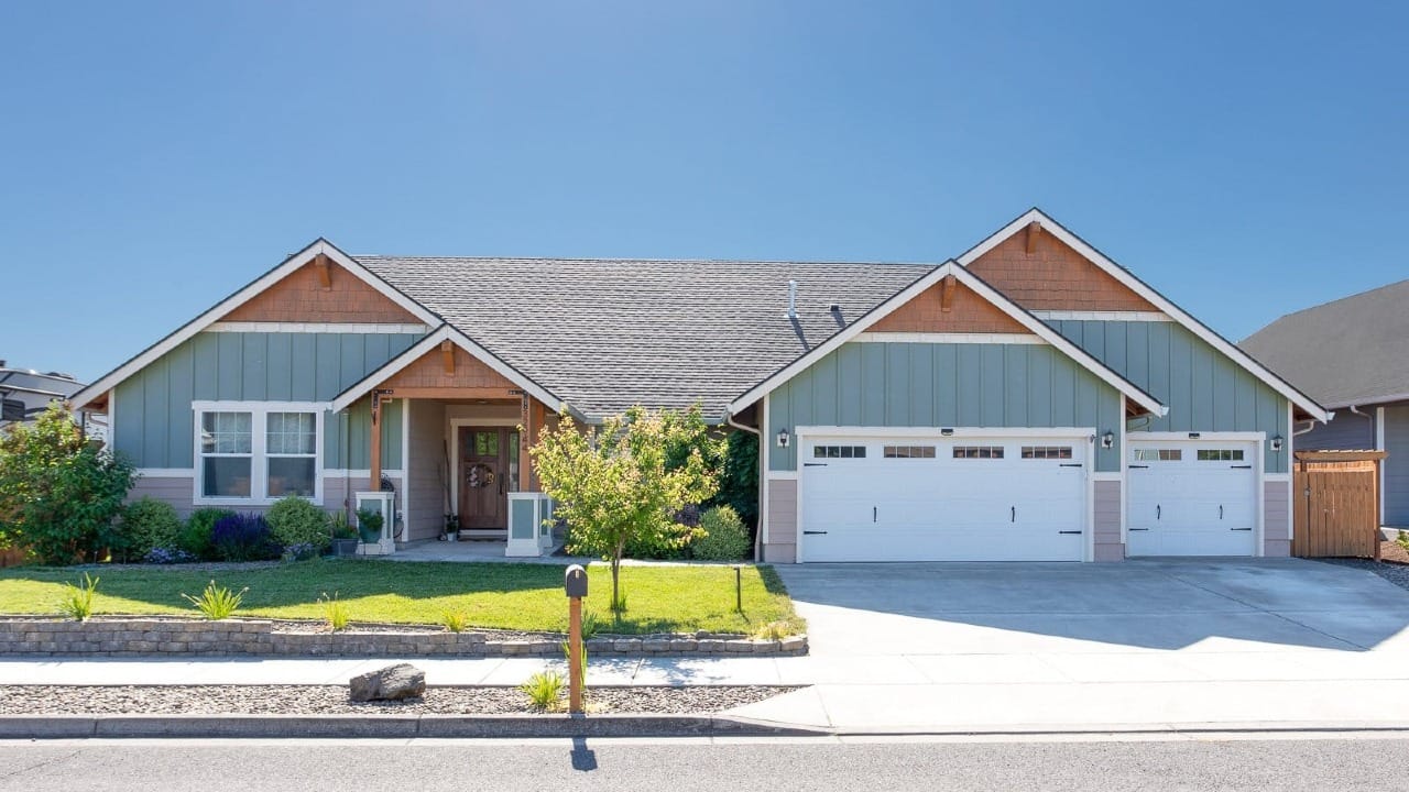 A blue and wood house with a sidewalk in front of it