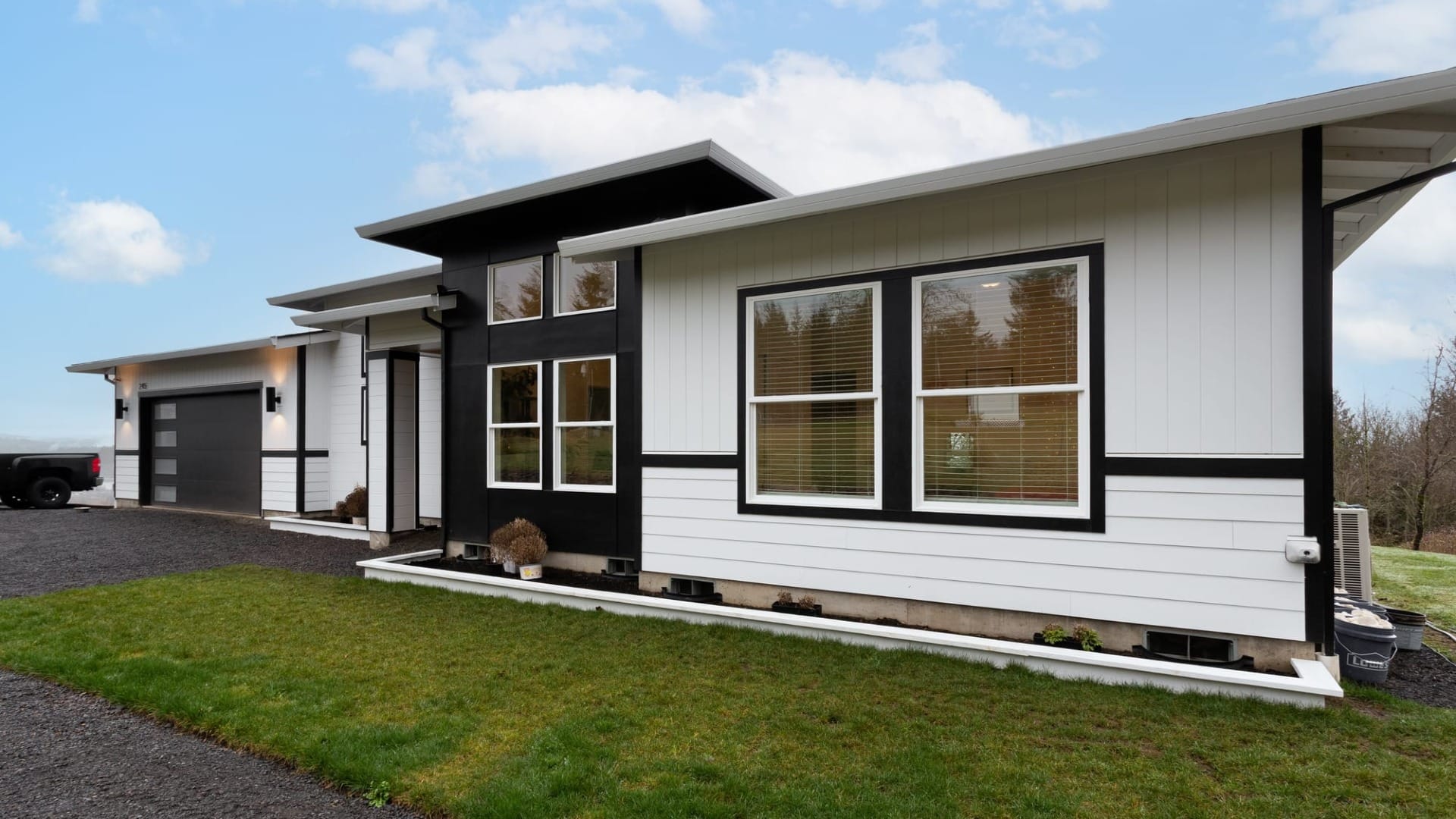 A black and white house in front of a gravel driveway