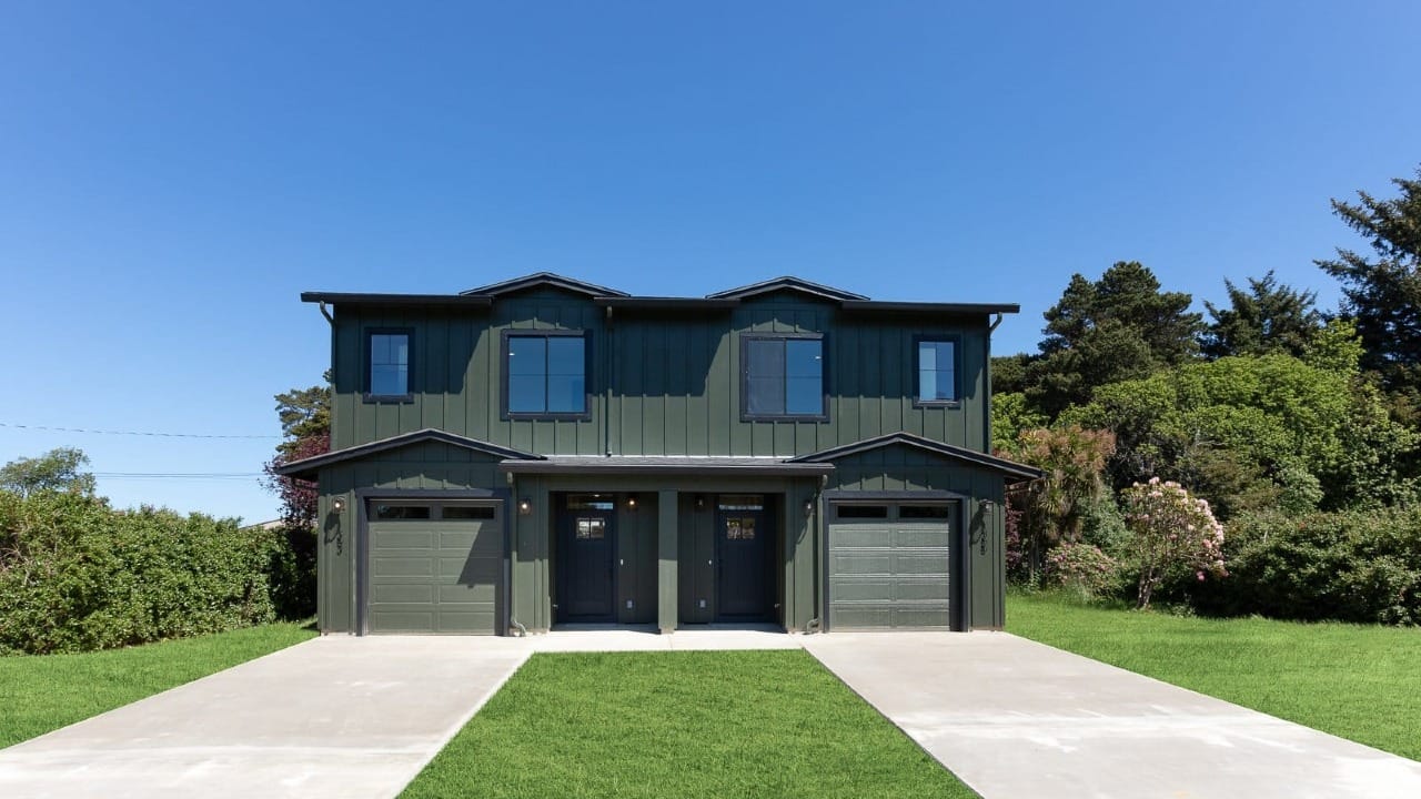 A green condo building with concrete driveways