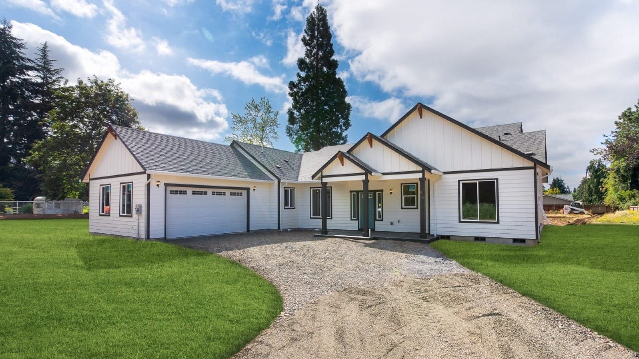 A white house in front of a gravel driveway